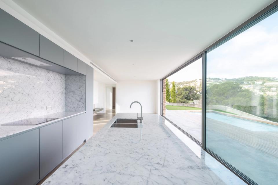 Detached single-family home with minimalist interiors and architecture designed to maximize natural light. The wooden staircase and large windows create a warm, elegant space connected to the outdoor landscape.