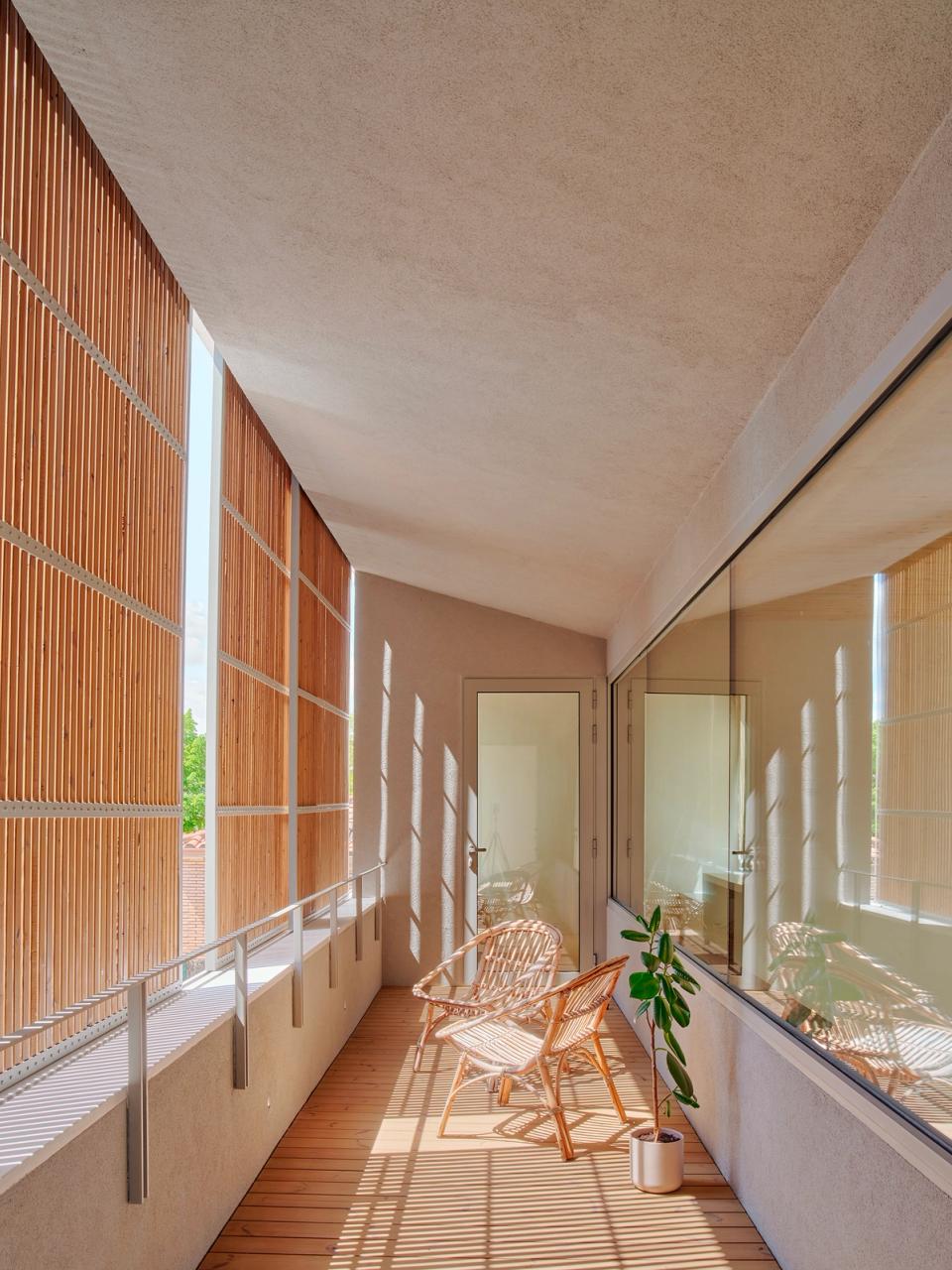 House in Girona with an outdoor gallery protected by wooden filters that regulate natural light and create comfortable resting areas. This house in Girona combines warm materials, natural shadows, and open architecture to strengthen the relationship with the outdoors