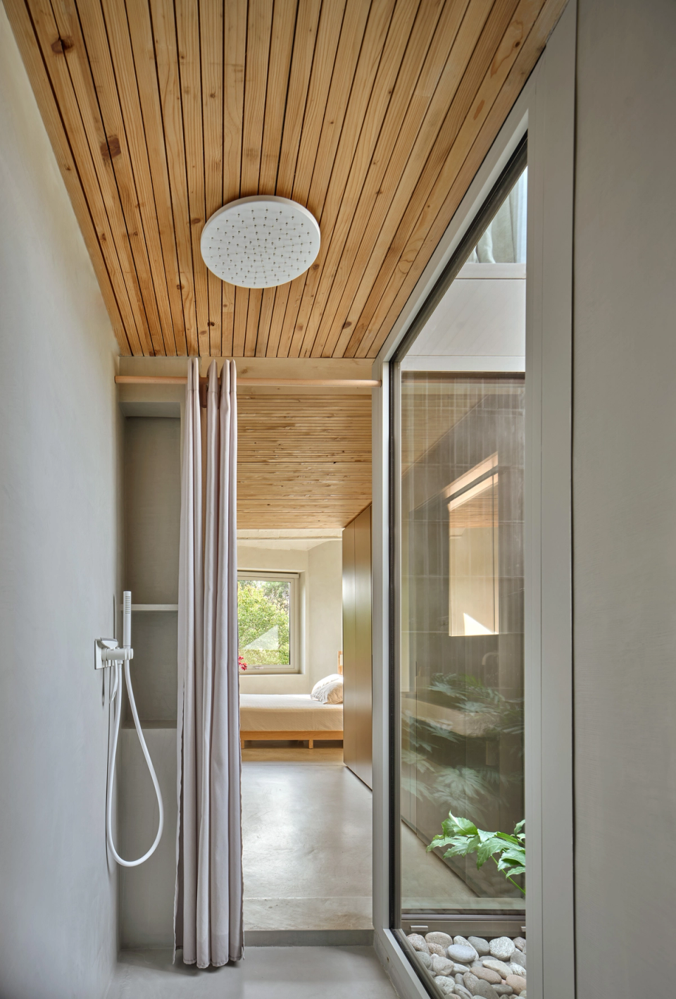 Housing renovation with a bathroom area open to an inner courtyard that enhances natural light and well-being. The renovation combines wood, vegetation and continuous materials to create intimate, calm spaces connected to the outdoors.