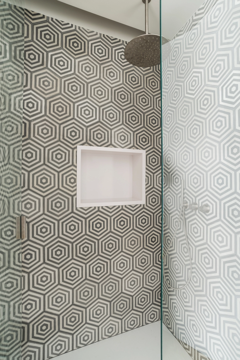 Interior renovation of a compact modern bathroom with integrated shower, geometric black-and-white tiles, and minimalist finishes that bring spaciousness, light, and functionality to the space.