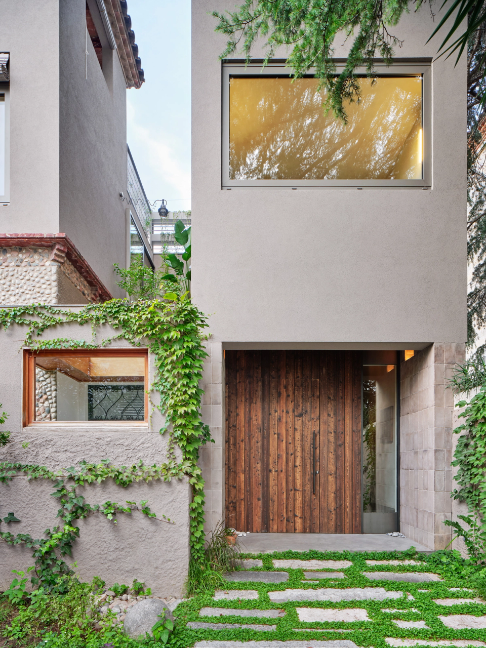 housing renovation with a contemporary façade integrated into the surroundings, combining natural textures, vegetation and noble materials. The renovation restores original elements and introduces new openings to enhance natural light and the connection with the outdoors.