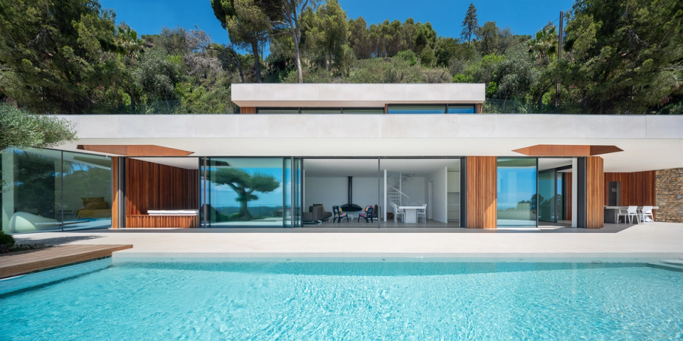 Detached single-family home with contemporary architecture featuring clean lines, large panoramic windows, and a spectacular outdoor swimming pool that enhances the connection between interior spaces and the natural surroundings. Finishes in wood, stone, and neutral tones bring warmth and elegance to a modern interior renovation designed to maximize natural light, spaciousness, and comfort.