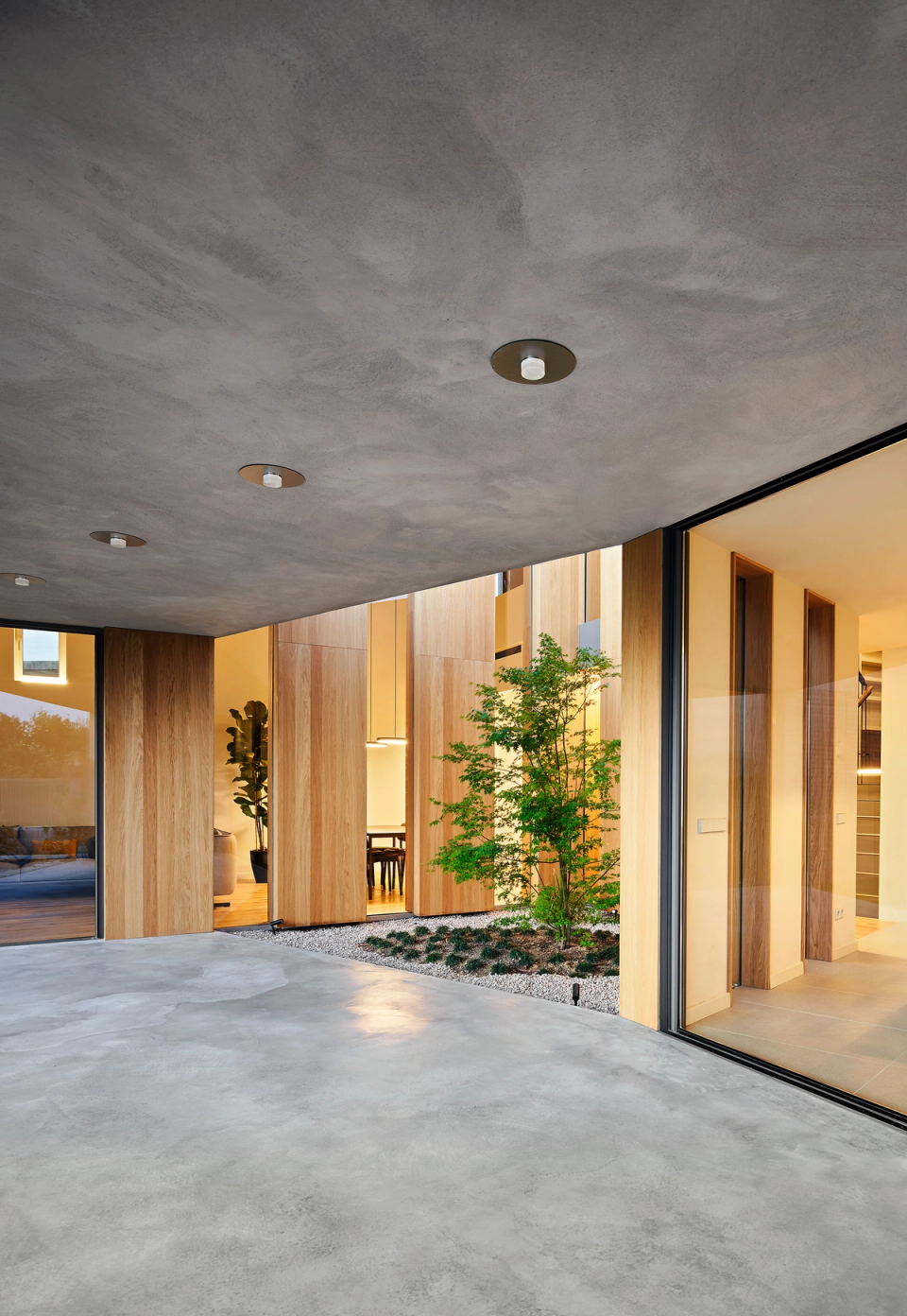 This single-family home embraces a warm and minimalist architecture, combining concrete, natural wood, and large glazed surfaces to create bright, open spaces connected to the outdoors.