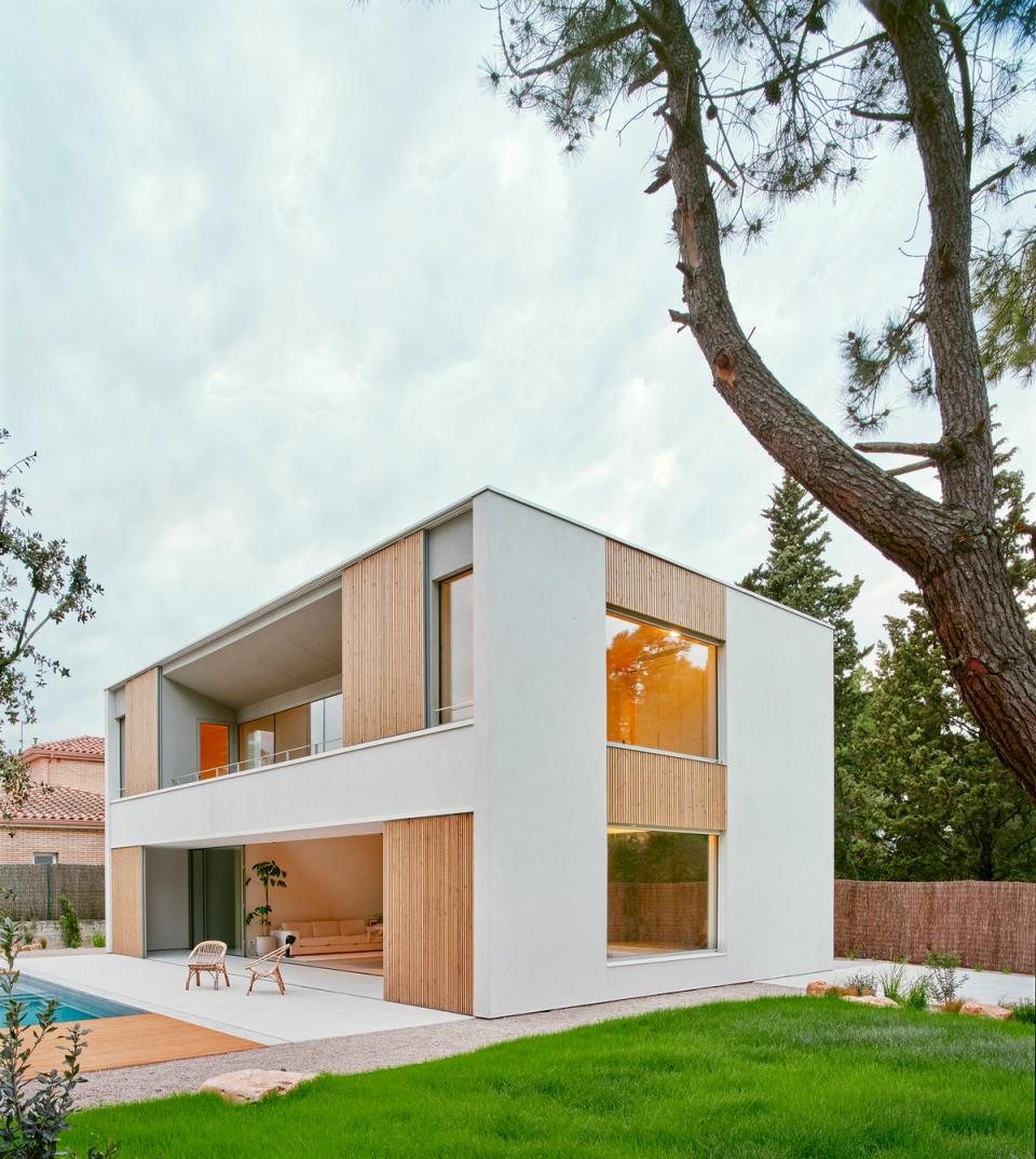 House in Girona with contemporary architecture organized around a double-height central space that connects the different areas of the house. This house in Girona features large openings, natural materials, and a fluid relationship between interior spaces, the garden, and family areas