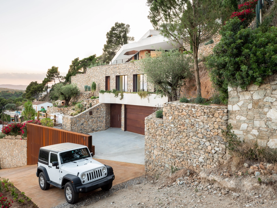 Detached single-family home with contemporary lines naturally integrated into the landscape and the site’s topography. The combination of natural stone, wood, and large white volumes brings warmth and modernity, while retaining walls and outdoor spaces create a harmonious connection with the Mediterranean surroundings. This architectural and interior renovation prioritizes natural light, spacious interiors, and the relationship between indoor Otand outdoor spaces, resulting in an elegant, functional home fully adapted to its natural context.