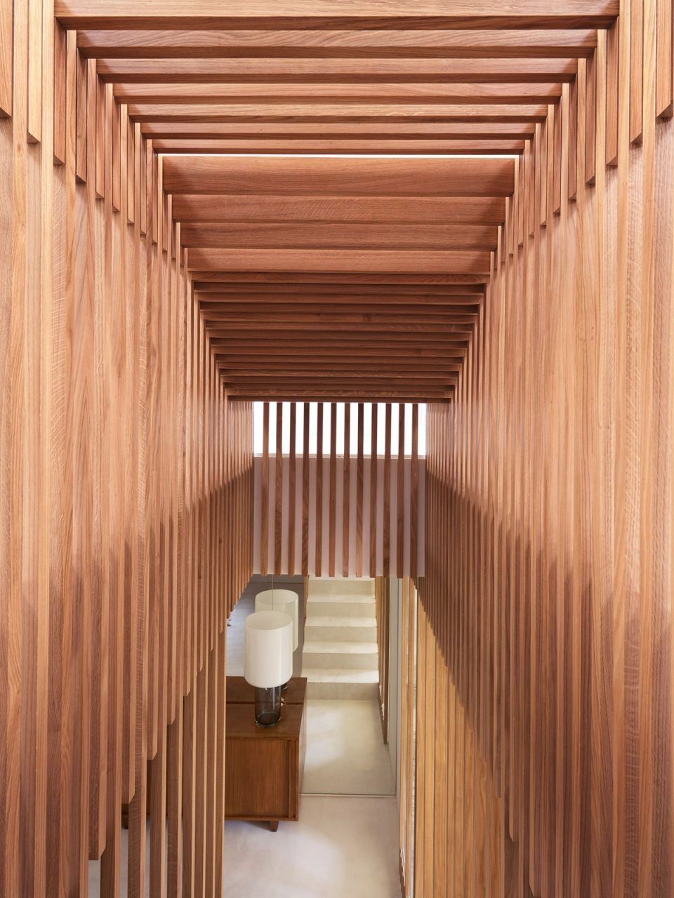 The renovation embraces noble materials and bespoke architectural solutions, such as this wooden slat cladding that adds depth, visual rhythm and continuity to the interior spaces.