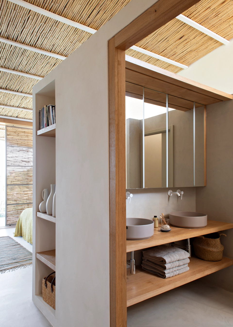 Bathroom area integrated within a contemporary detached house, featuring natural finishes, wooden furniture and an open layout that enhances spaciousness and brightness. The use of warm textures, neutral tones and handcrafted elements creates a relaxed and elegant atmosphere visually connected to the rest of the home.