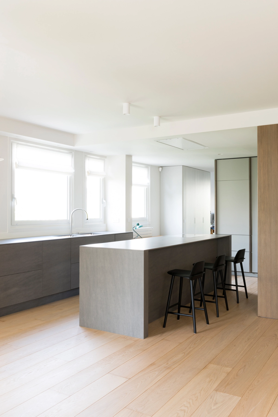 Minimalist interior renovation with an open contemporary kitchen, integrated dark wood cabinetry, modern kitchen island, open and bright space, natural linen curtains, light oak parquet flooring, elegant and functional interior design, clean refined lines, iconic pendant lighting, warm and sophisticated atmosphere, contemporary Nordic-style modern interior design.