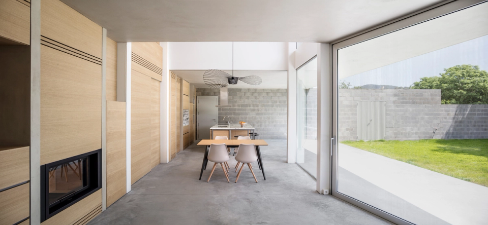 Dining area of a detached single-family home with large panoramic windows and direct views of the private garden. Contemporary architecture creates a fluid connection between interior and exterior, enhancing natural light, visual spaciousness, and residential comfort.