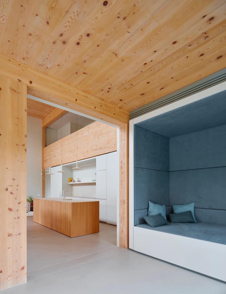 House in Girona with open and visually connected spaces integrating relaxation, dining, and living areas into a single fluid environment. This house in Girona combines natural wood, built-in furniture, and large openings to enhance natural light and interior comfort