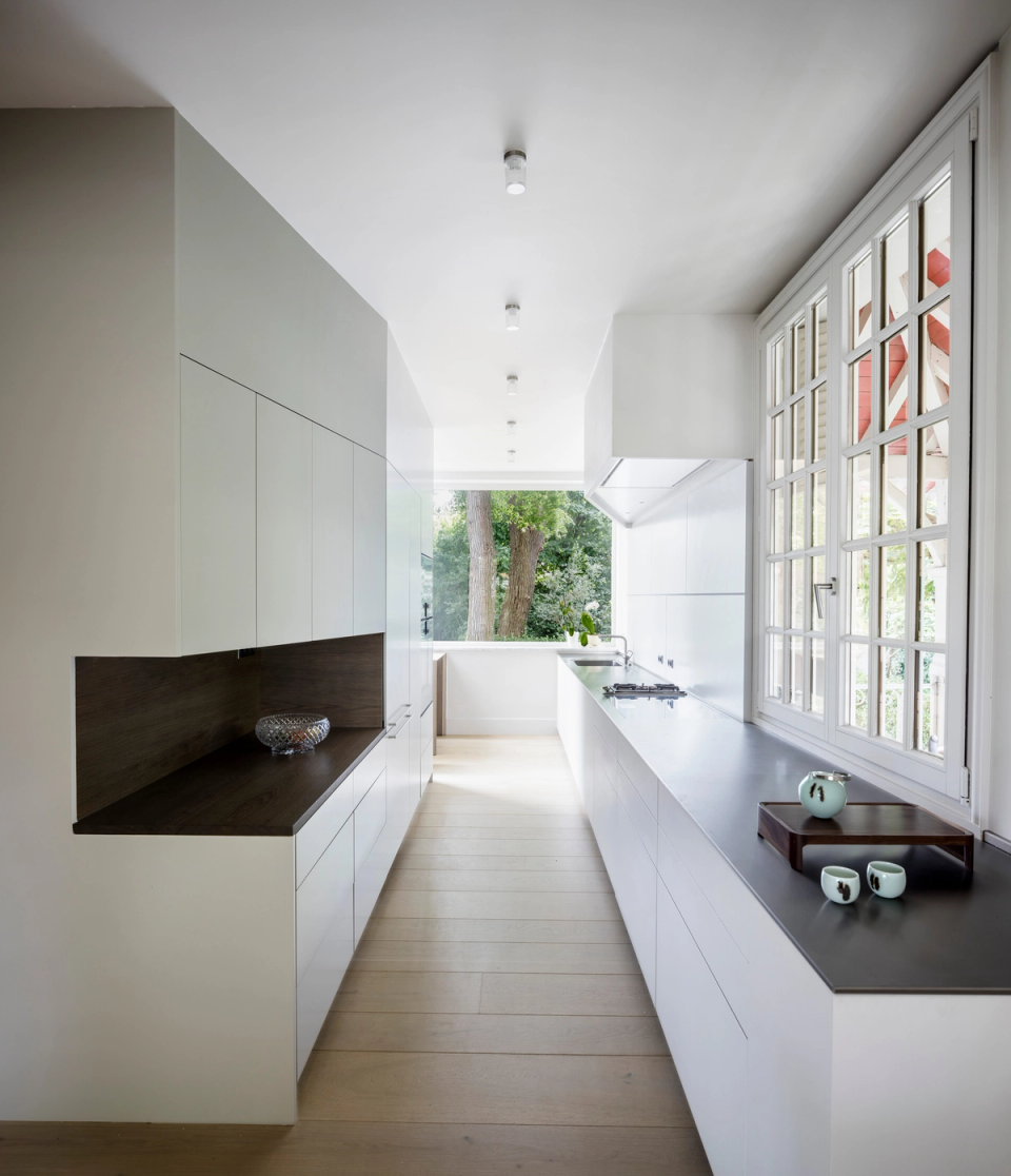 Interior renovation of a kitchen featuring a large sculptural marble island as the centerpiece of the space. The intervention combines the classical elegance of molded ceilings and original carpentry with contemporary elements and warm-toned details, creating a sophisticated, luminous, and highly distinctive atmosphere.