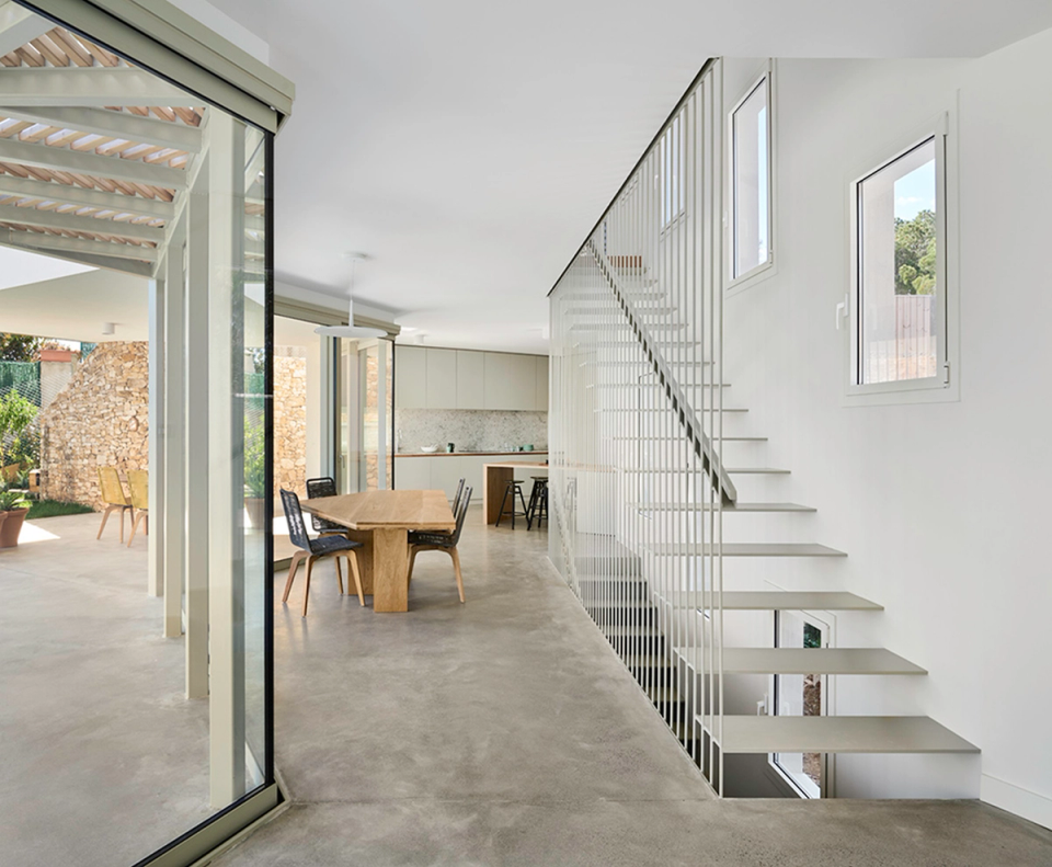 Modern detached single-family home with open interior spaces that prioritize natural light, visual fluidity, and connection with the outdoors. The suspended metal staircase and minimalist finishes bring lightness and elegance to a contemporary architecture conceived to provide spaciousness and comfort.