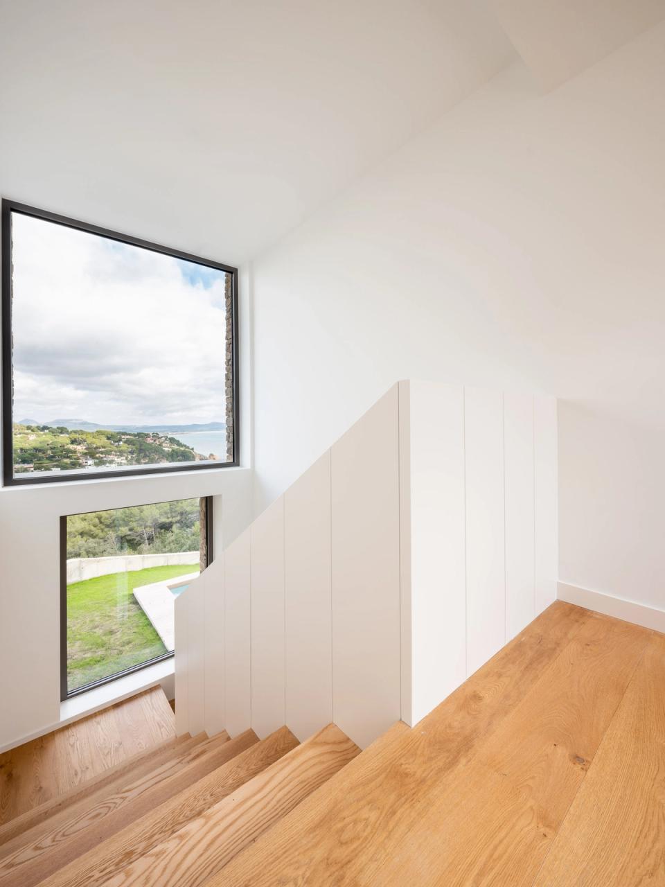 Detached single-family home with bright interior spaces and large panoramic windows overlooking the landscape. Natural wood finishes and clean lines bring warmth, spaciousness, and a direct connection with the outdoor environment.
