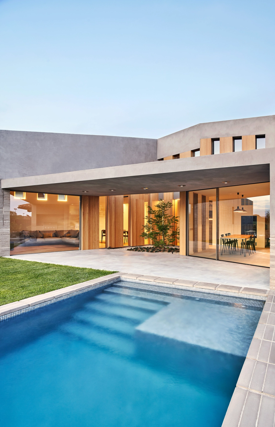 This single-family home stands out for its open and bright architecture, with large glazed surfaces connecting the interior spaces to the swimming pool and garden. The combination of mineral textures and wooden cladding adds warmth and elegance to a contemporary and functional architectural ensemble.
