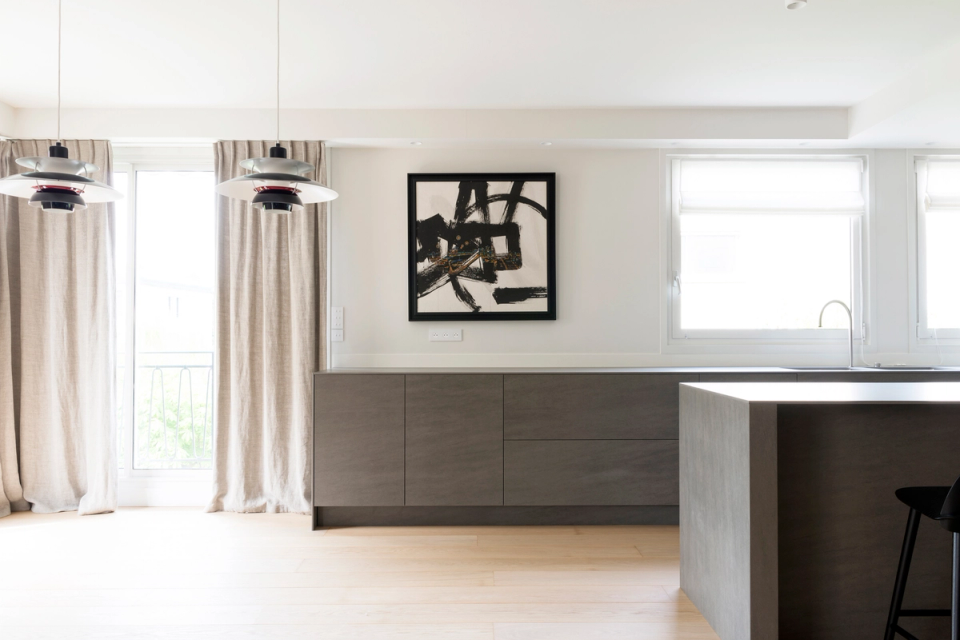 Minimalist kitchen interior renovation with a modern central island, open and bright space, contemporary design with clean lines, anthracite gray and natural wood cabinetry, light oak parquet flooring, designer black stools, integrated Nordic-style kitchen, elegant and functional interior design, abundant natural light, warm and sophisticated atmosphere, high-end modern interior architecture.