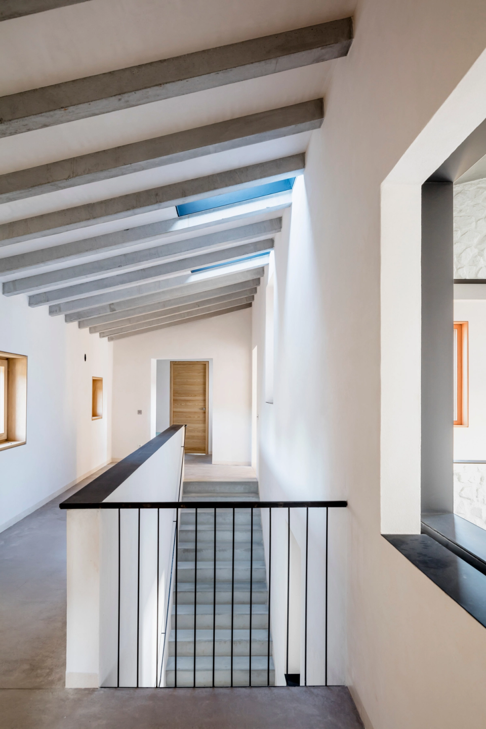 Interior space of a full renovation that combines contemporary architecture and traditional materials to create a unique and luminous atmosphere. The restored stone walls bring texture and authenticity, while the geometric openings and skylights enhance the flow of natural light and the visual connection between spaces. Minimalist finishes, sloped ceilings, and neutral-toned details reinforce an elegant and timeless aesthetic. This full renovation stands out for its modern reinterpretation of traditional architecture, prioritizing spaciousness, comfort, and brightness.