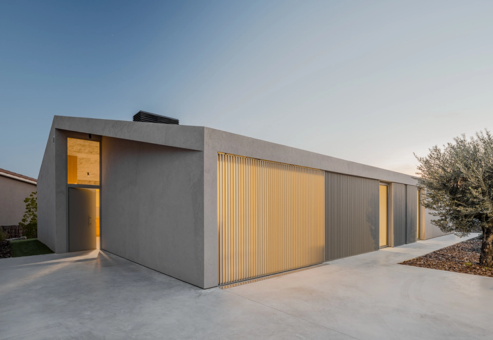 This single-family home is defined by a compact and minimalist architecture, with a refined façade that combines neutral textures and vertical metal filters to control light and preserve privacy. Integrated lighting and horizontal lines reinforce the home’s contemporary elegance, creating a sober, warm, and timeless image.