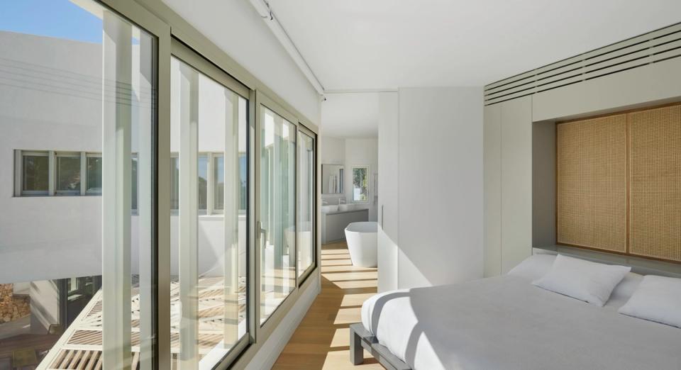 Bright bedroom in a contemporary detached single-family home with large windows, minimalist finishes, and visual connection with outdoor spaces. The interior stands out for its natural light, neutral tones, and functional design focused on comfort and residential efficiency.
