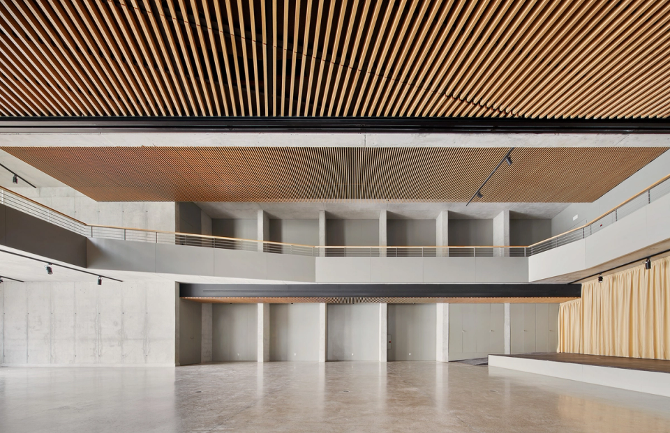 Main hall of a cultural center designed with criteria of spaciousness, functionality, and acoustic comfort. Large wooden slat ceilings, combined with exposed concrete and perimeter walkways, provide a contemporary and elegant image to this multipurpose space. The integrated stage and open layout allow the cultural center to adapt to conferences, exhibitions, stage activities, and community events in a modern and bright environment.