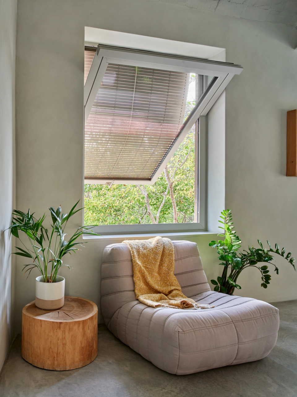 Housing renovation with a resting area lit by a large window facing outdoors. The renovation combines natural light, vegetation and warm materials to create a calm, comfortable and welcoming atmosphere