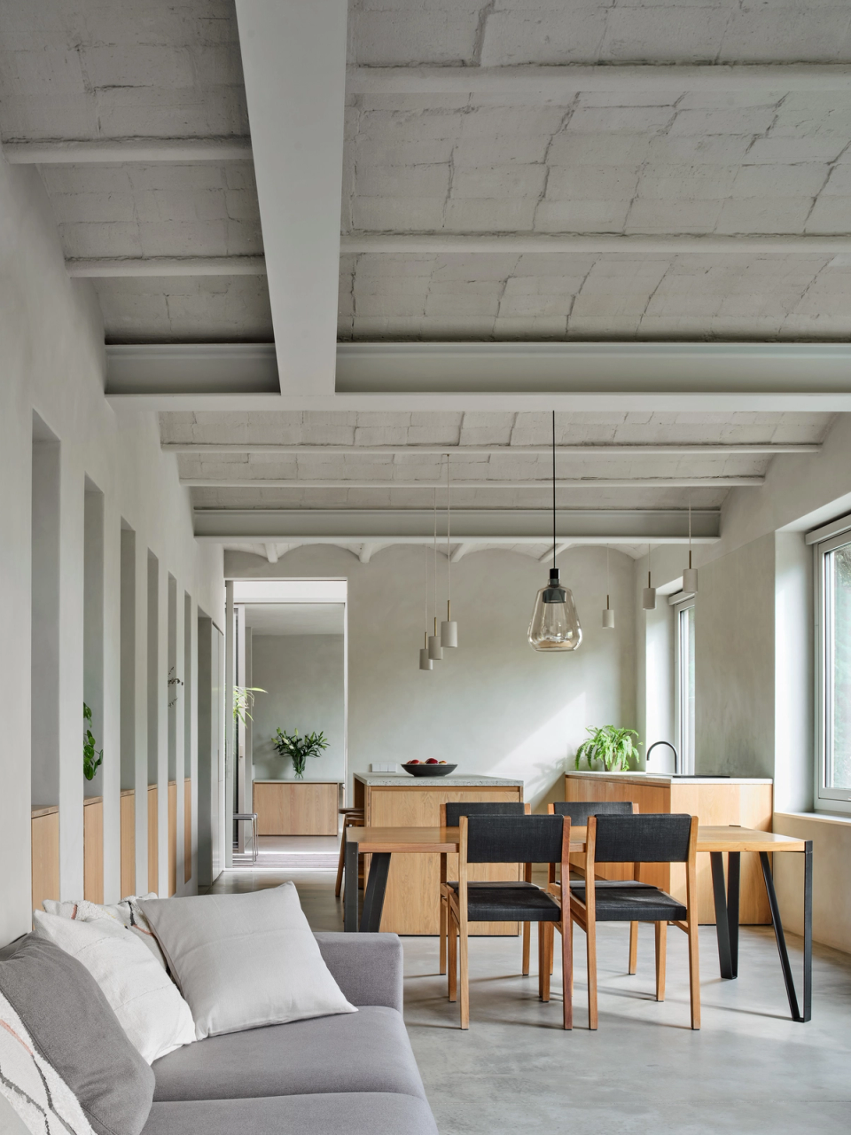 Housing renovation with an open layout integrating living room, dining room and kitchen in a spacious and bright area. The renovation preserves original ceiling elements and incorporates natural materials to enhance the contemporary and welcoming character of the interiors.