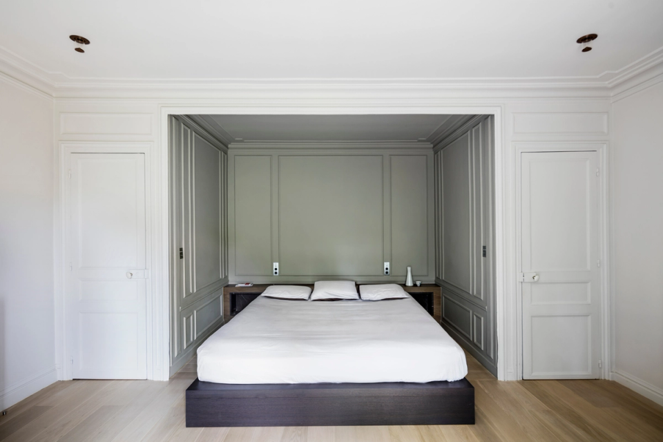 Interior renovation of a master bedroom with a serene and elegant proposal combining symmetry, classical moldings, and a palette of neutral tones. The project enhances natural light and a sense of calm through clean lines, integrated furniture, and contemporary finishes that respect the original architectural essence of the space.
