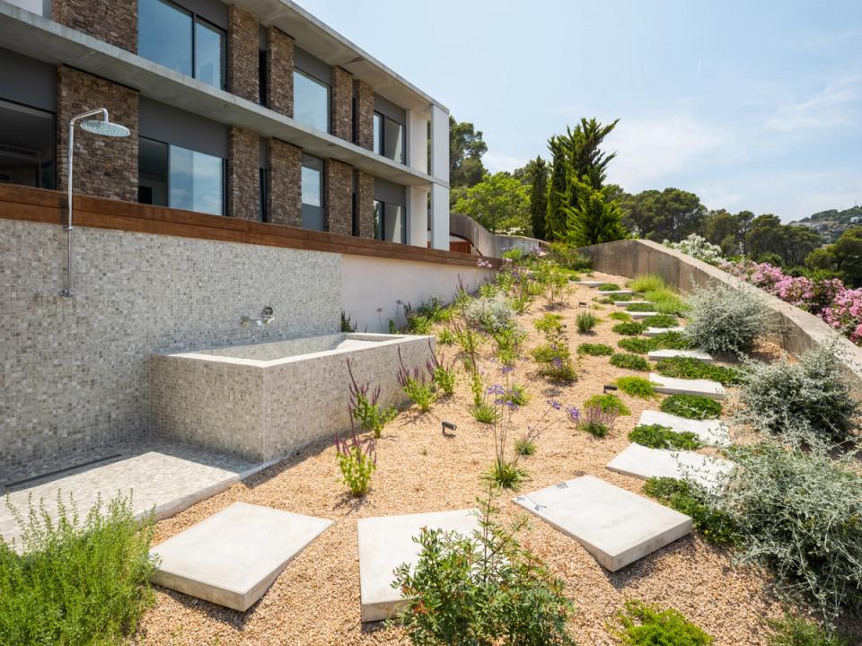 Detached single-family home with auxiliary spaces integrated into the terrain and designed with premium materials. The combination of natural wood, exposed concrete, and minimalist lines brings functionality and architectural coherence to the outdoor composition.