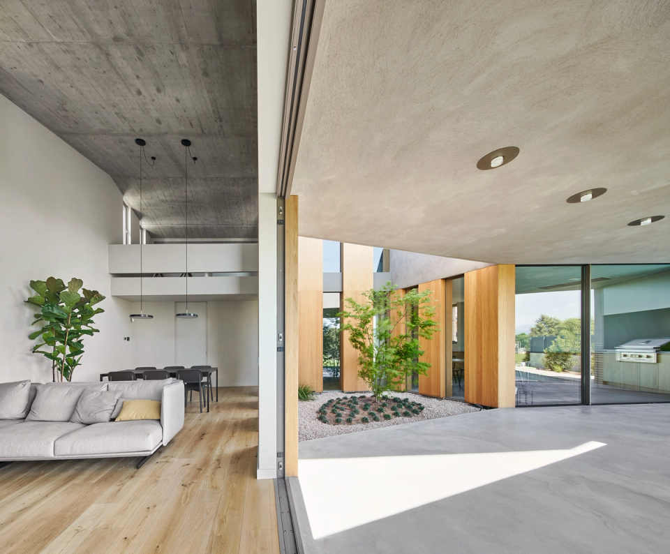 This single-family home embraces open and continuous spaces that blur the boundaries between interior and exterior. The combination of exposed concrete, natural wood, and large sliding enclosures creates a contemporary, luminous architecture fully connected to the central courtyard.