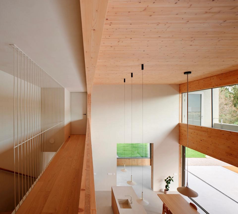 House in Girona with open interior spaces, double-height ceilings, and natural materials that enhance light and spaciousness. This house in Girona uses wood and large openings to create a healthy, warm atmosphere connected to the outdoors