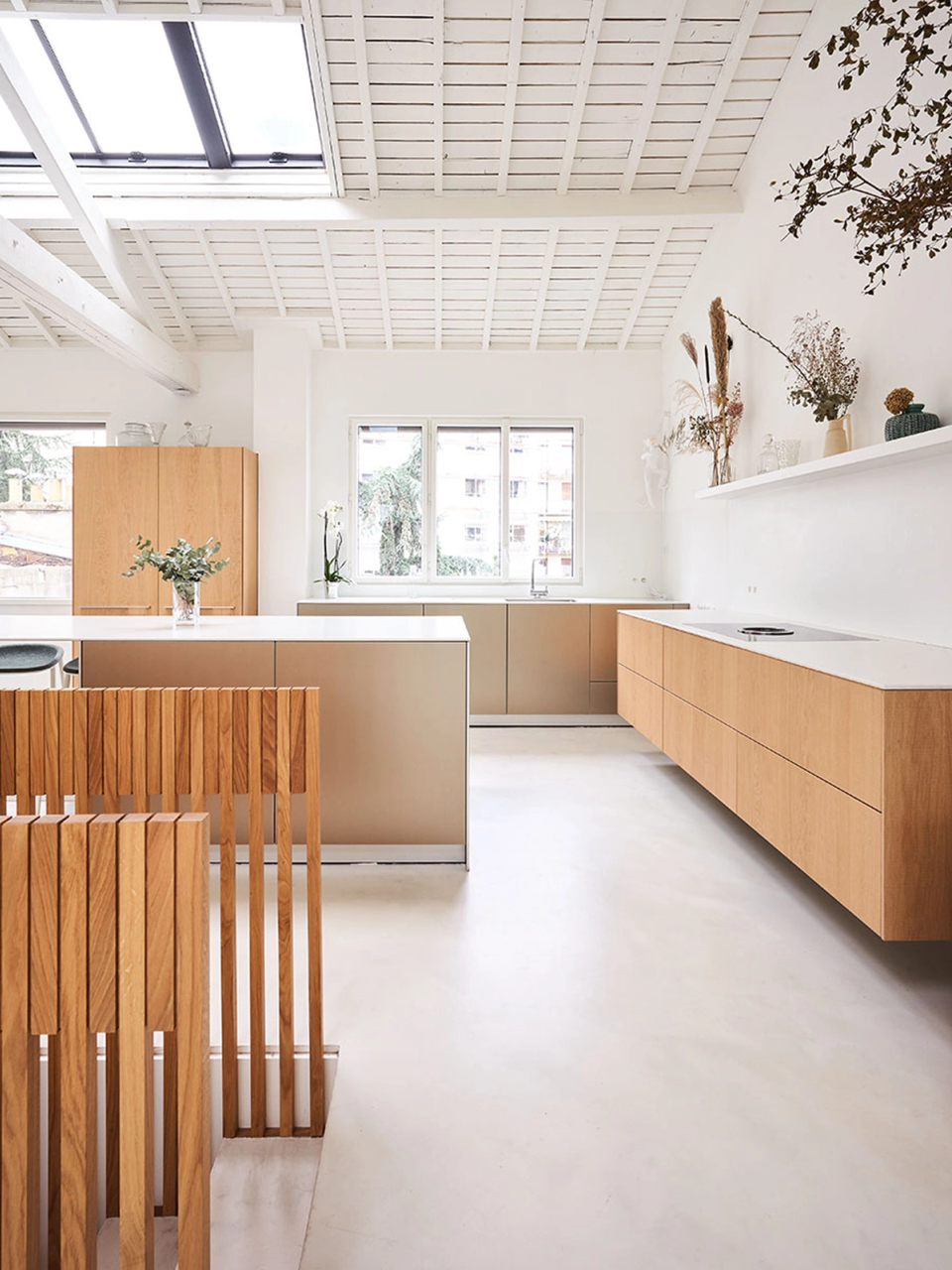 This full renovation enhances natural light and the sense of spaciousness through an open layout and warm contemporary materials. The restoration of the original exposed wooden roof, combined with white finishes and natural wood elements, creates an elegant, functional and visually connected space between the different common areas.