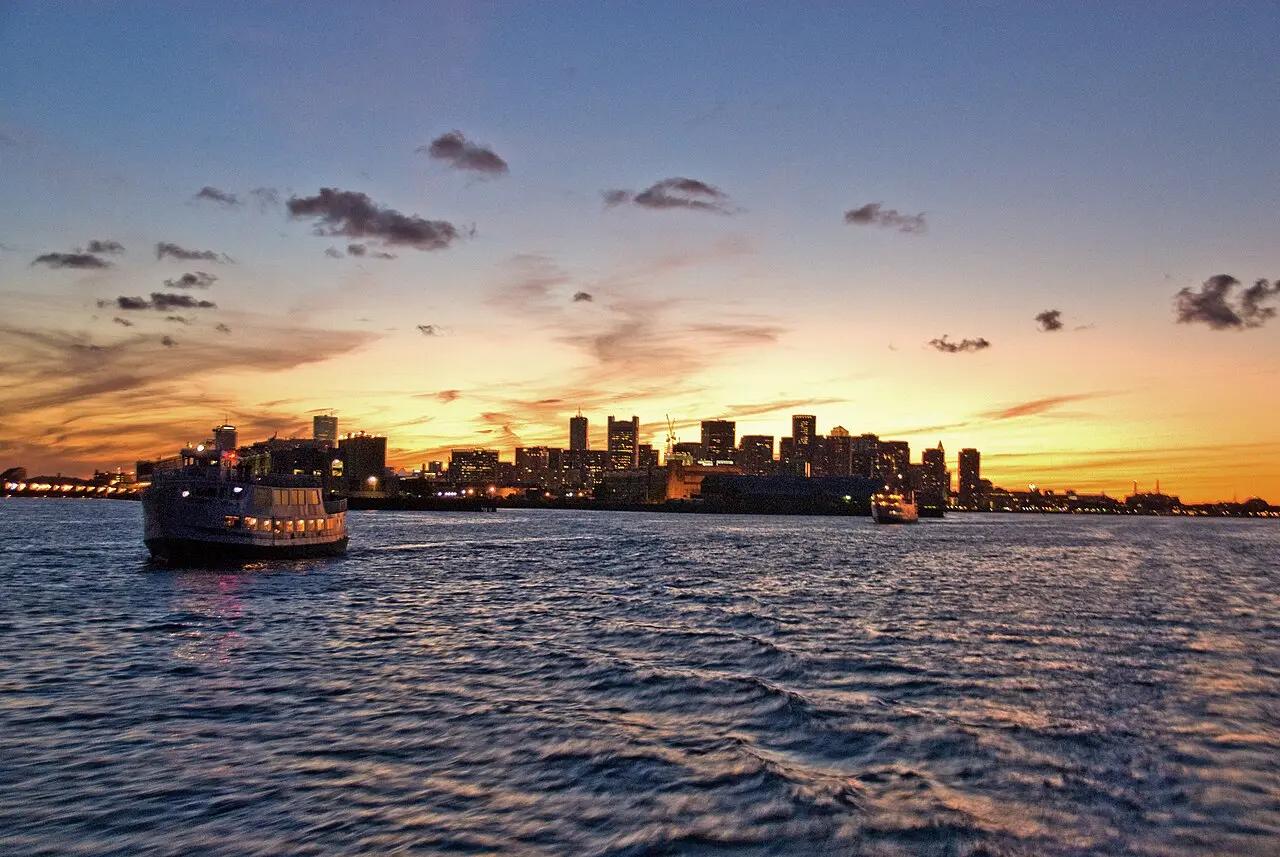 A ferry crossing Boston Harbor beneath a warm September sunset