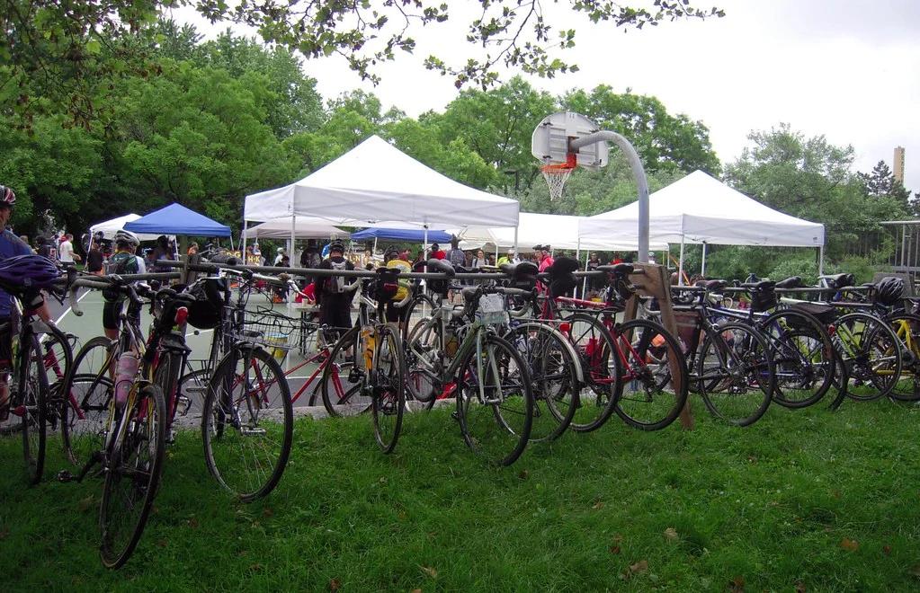 Rows of road bicycles on temporary racks beside event tents and a basketball court at the 2012 Bikes Not Bombs Bike-A-Thon.