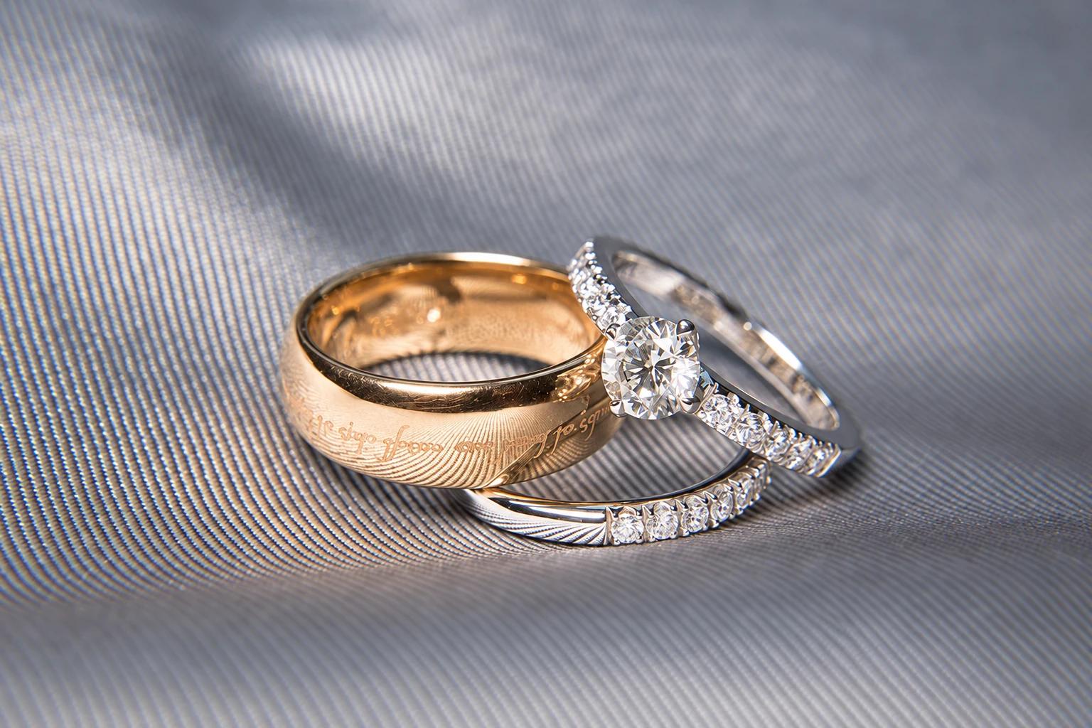 A gold wedding band beside a diamond solitaire and an eternity ring