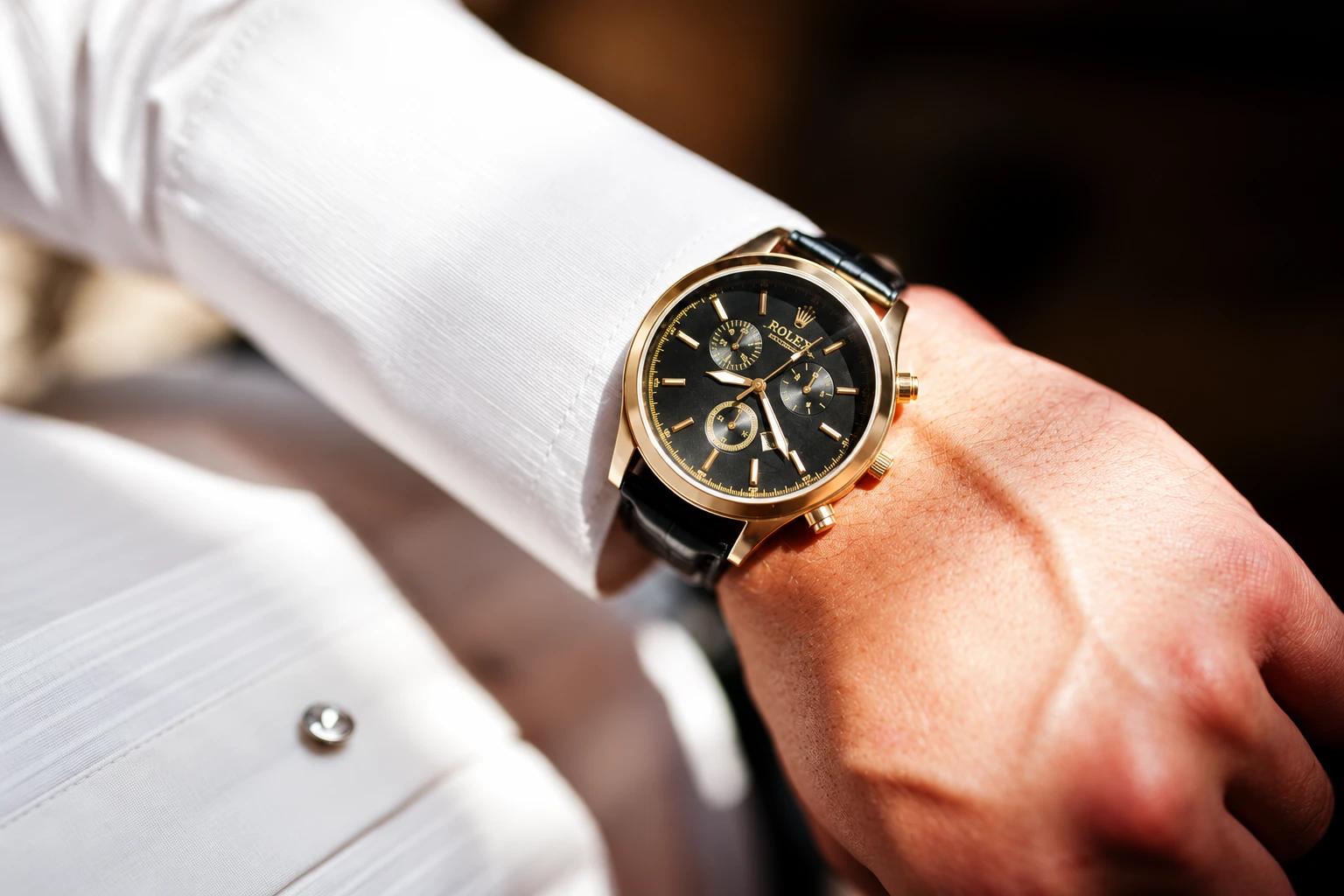 A gold Rolex chronograph on the wrist, worn with a white shirt cuff