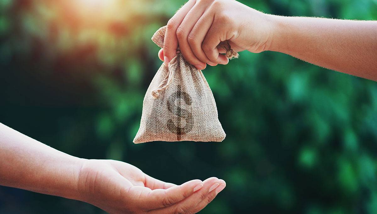 one person hands bag of money to another