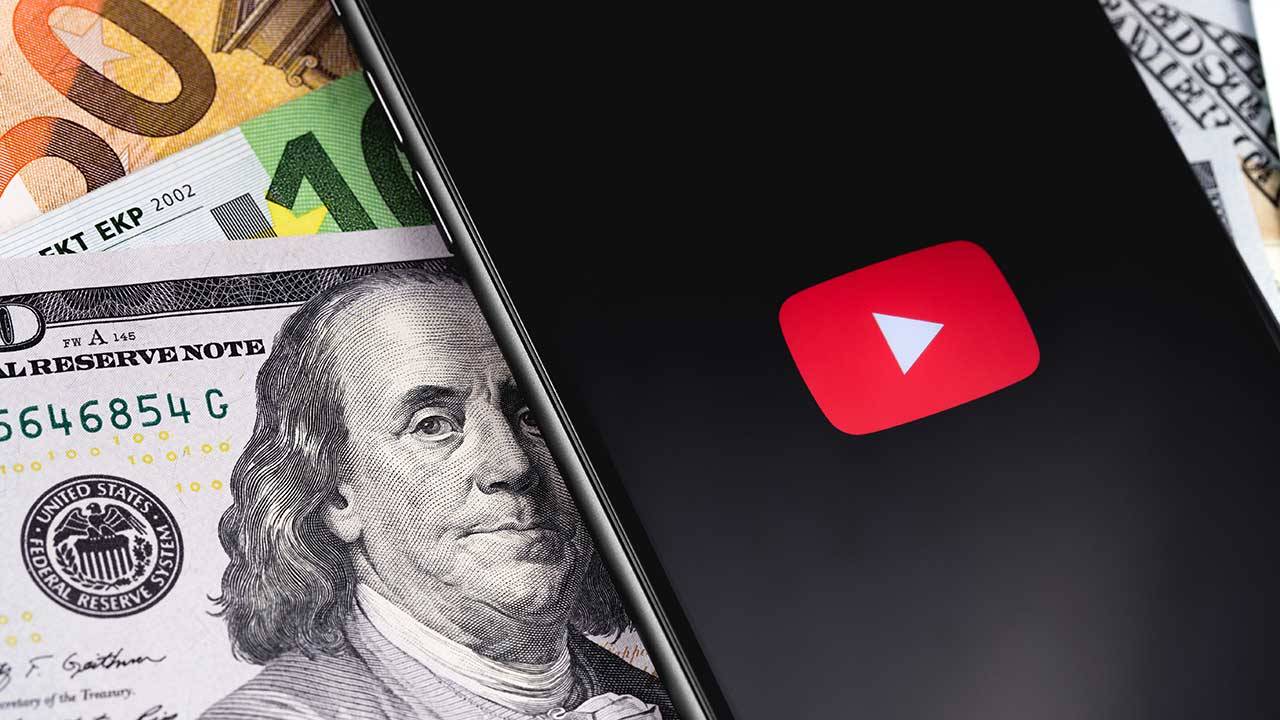 Phone showing the YouTube logo and sitting on paper money