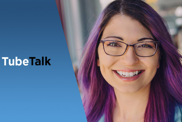 Smiling woman with purple hair and glasses beside blue TubeTalk logo background.