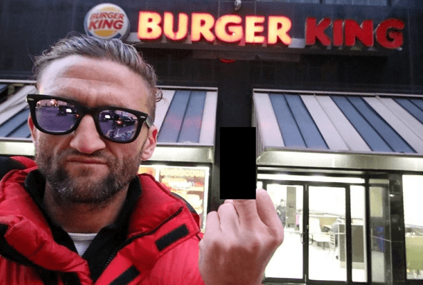 Man in sunglasses and red jacket making a gesture outside a Burger King restaurant at night