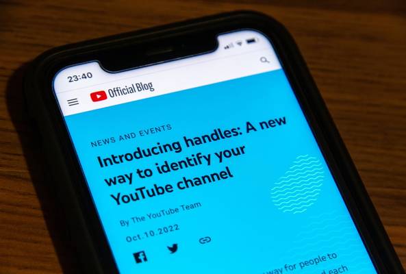 Smartphone showing YouTube Official Blog article about introducing handles for channels.