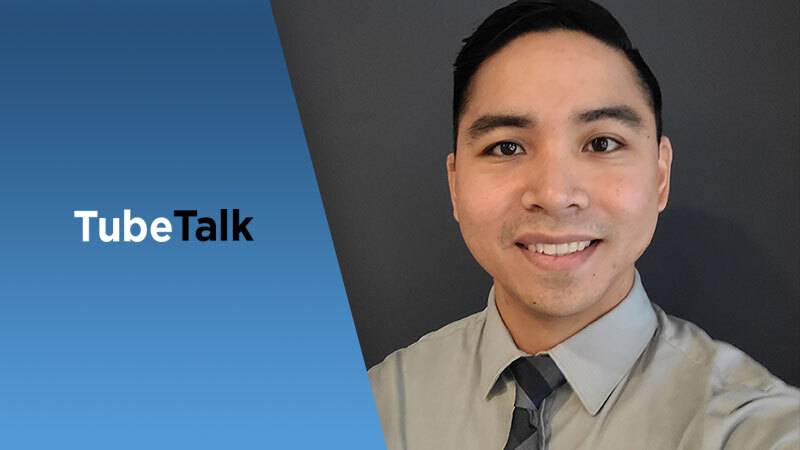 Young professional man smiling next to blue background with TubeTalk logo text