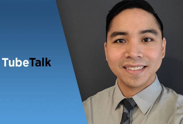 Young professional man smiling next to blue background with TubeTalk logo text
