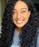 Smiling woman with long curly black hair wearing a gray shirt in natural light