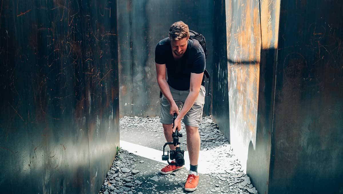 Male YouTuber filming a low angle shot in an alleyway