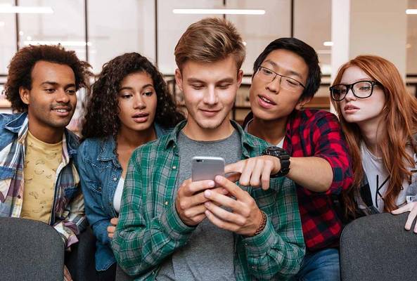 Diverse group of young adults looking at a smartphone together in a casual setting