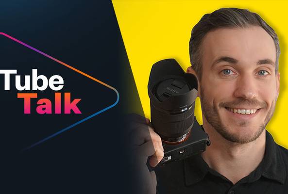 Smiling man holding camera next to Tube Talk logo on black and yellow background.