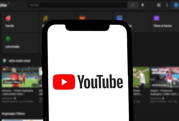 Smartphone screen showing YouTube app logo with blurred YouTube homepage in background