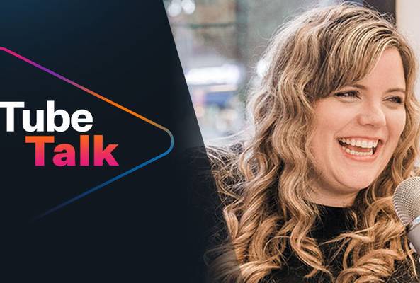 Smiling woman speaking into microphone with Tube Talk logo on dark background
