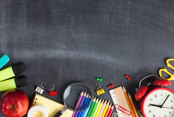 Back to school supplies including pencils, clock, apple, and markers on chalkboard background