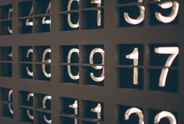 Close-up of illuminated vintage mechanical scoreboard numbers in metal grid display.
