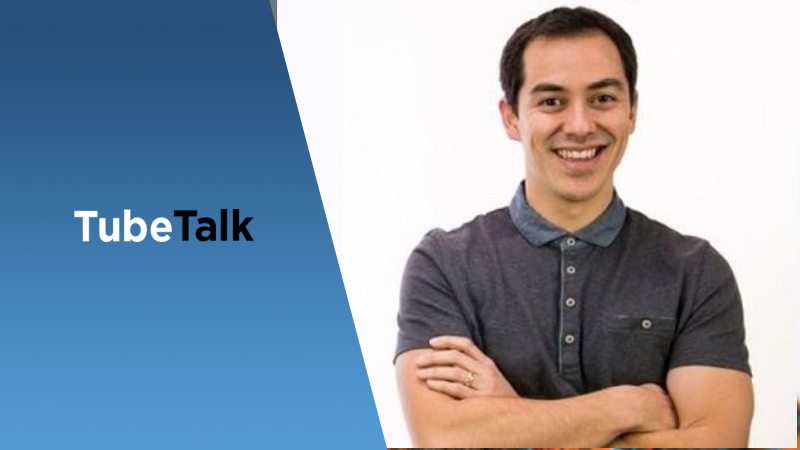 Smiling man in gray polo shirt with TubeTalk blue and white logo on left side background